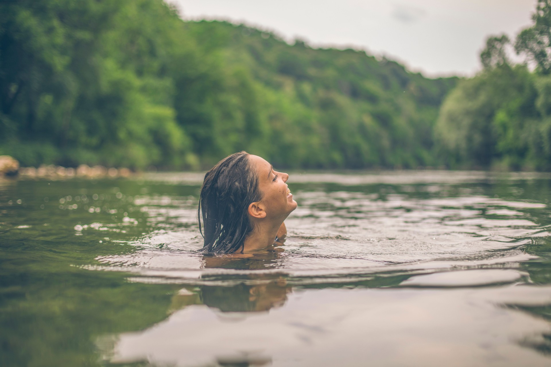 Young woman swims down lakeshore, in summer